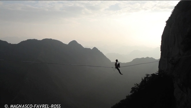 Compétition highline en Chine, athlète sur la ligne face au couchr de soleil.